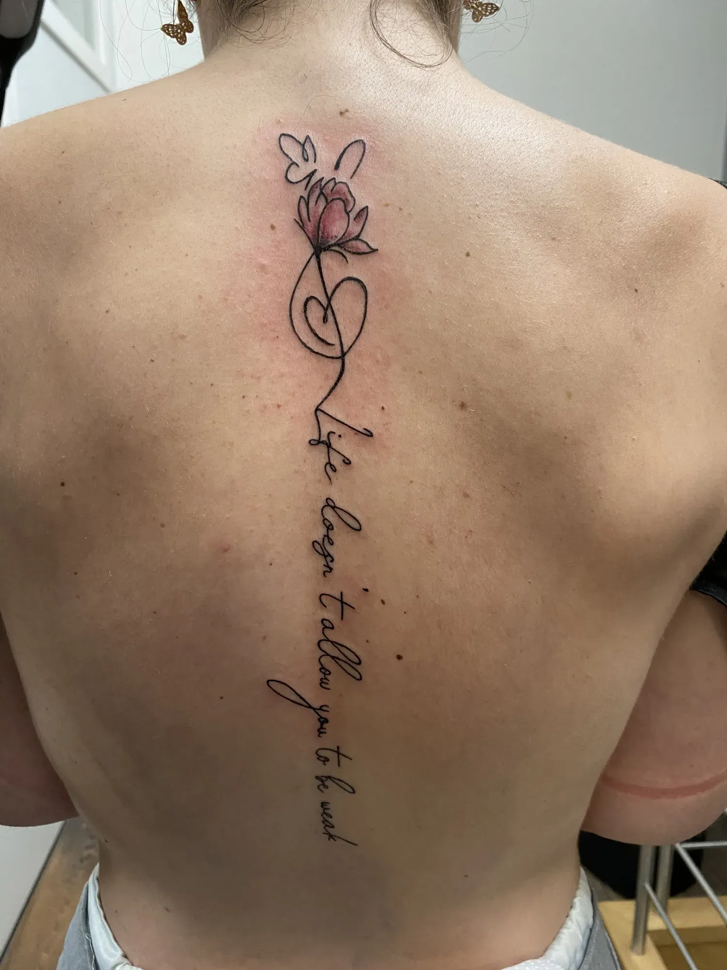 Black & grey sierschrift met bloem op de ruggengraat, tattoo Gent